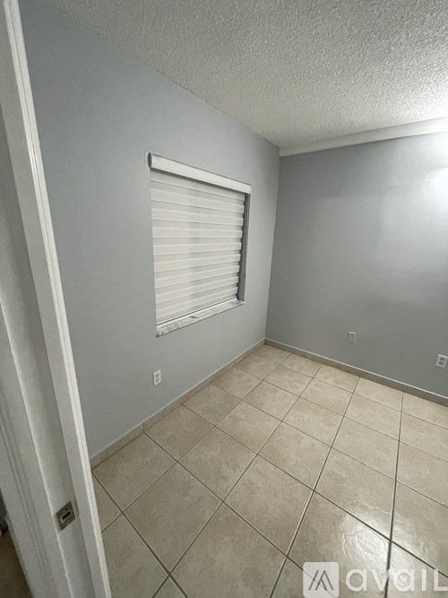 A room with a tiled floor and a window with blinds.
