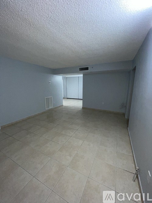 A room with tiled flooring and a window with blinds.