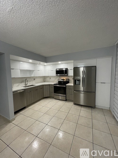 A kitchen with white cabinets and a stainless steel refrigerator.
