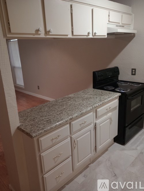 A kitchen with a granite countertop and black appliances.