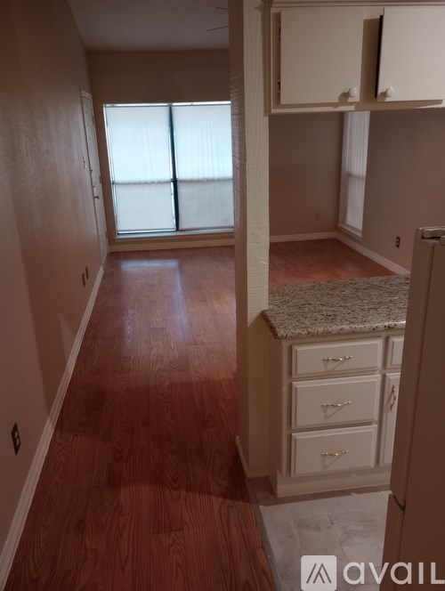 A room with wooden floors and a window with blinds.