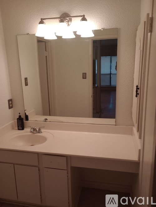 A bathroom with a sink, mirror, and light fixture.