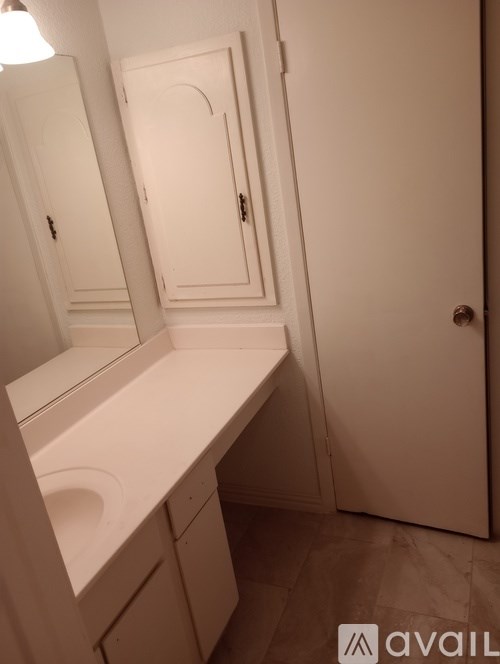 A white bathroom with a sink and mirror.