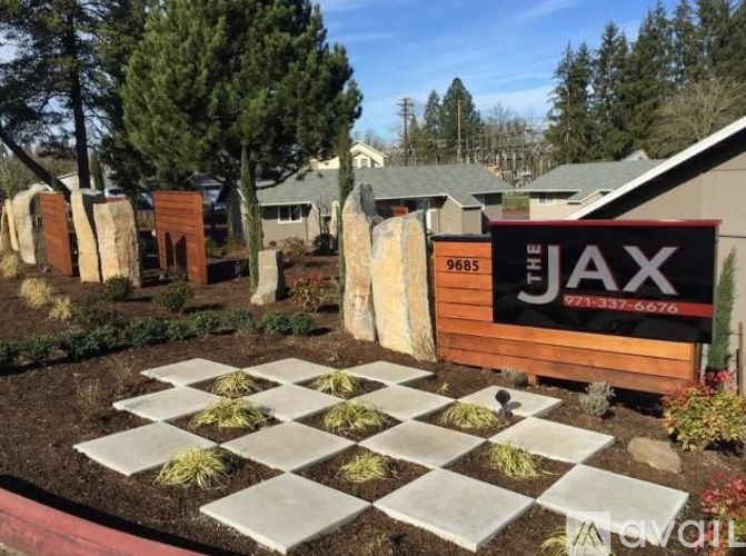 A garden with a sign that reads "JAX" in front of a house.