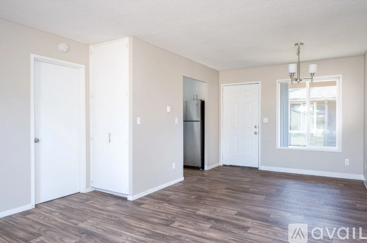 A spacious room with wood flooring and a large window.