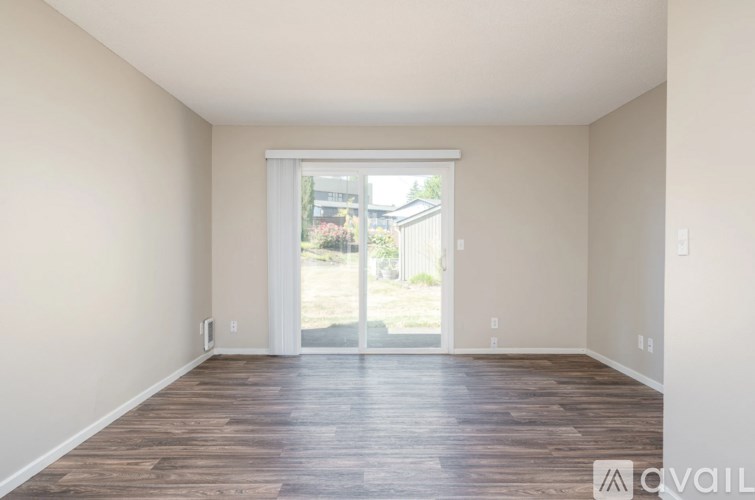 A room with wooden floors and a sliding glass door leading outside.