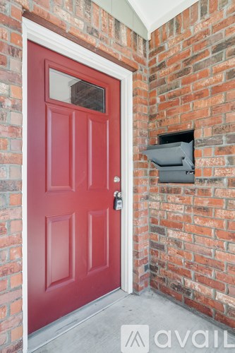 A red door is on the left side of a brick wall.