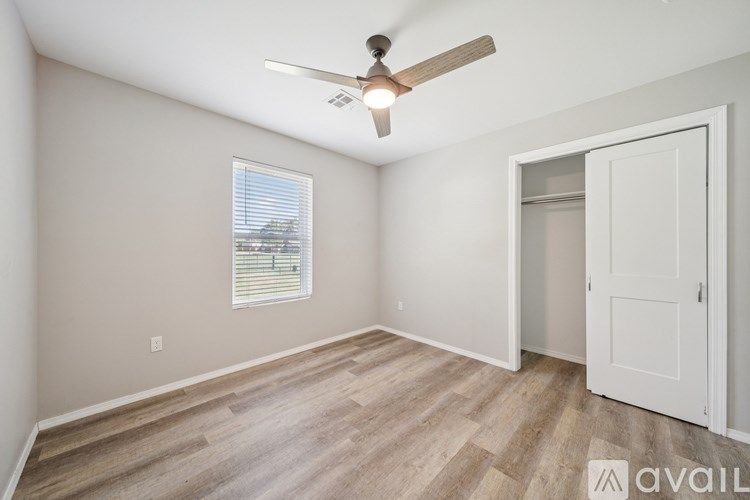 A room with a ceiling fan and a door leading to another room.