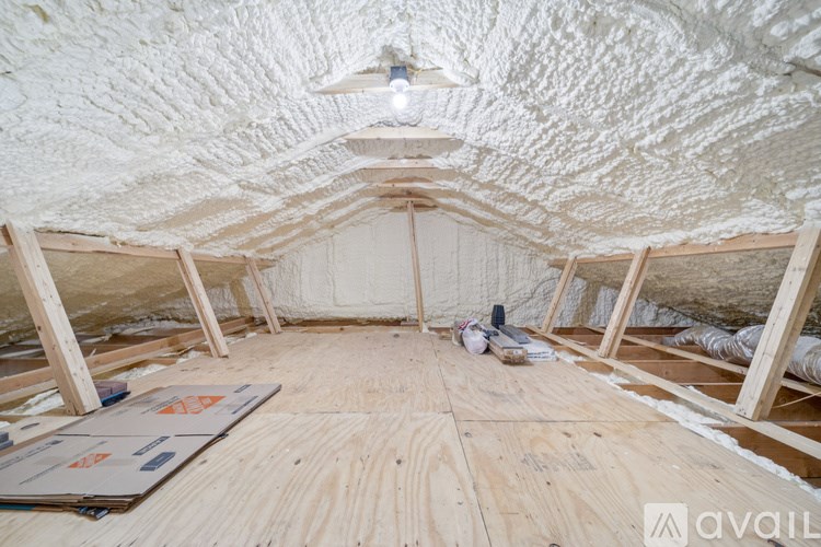 A room under construction with wooden flooring and exposed ceiling.