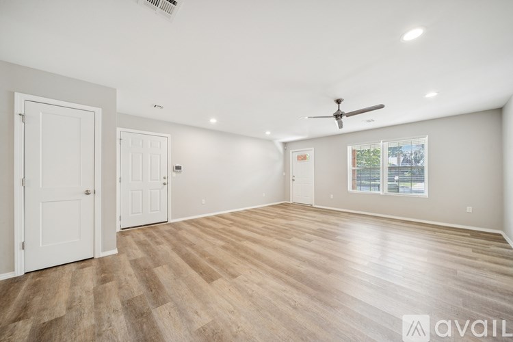 A spacious room with wooden flooring and a ceiling fan.