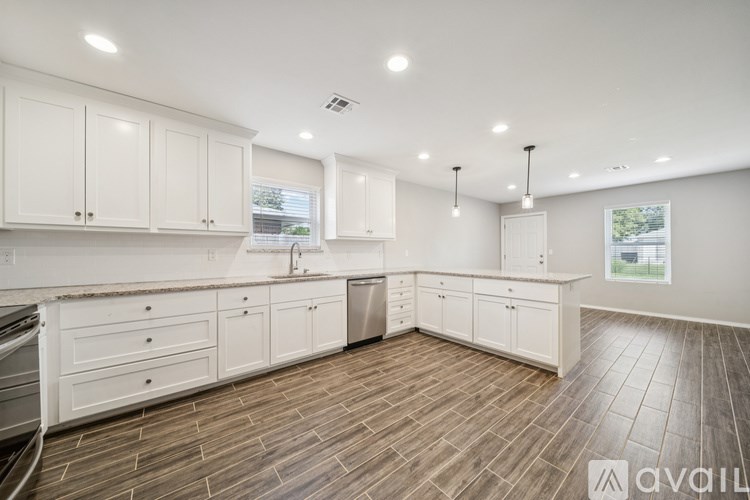 A kitchen with white cabinets and a wooden floor.
