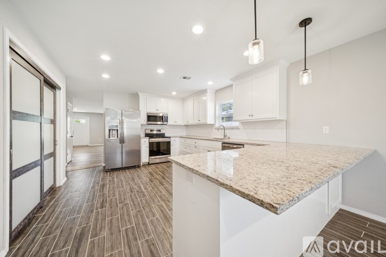 A modern kitchen with a marble countertop and white cabinets.