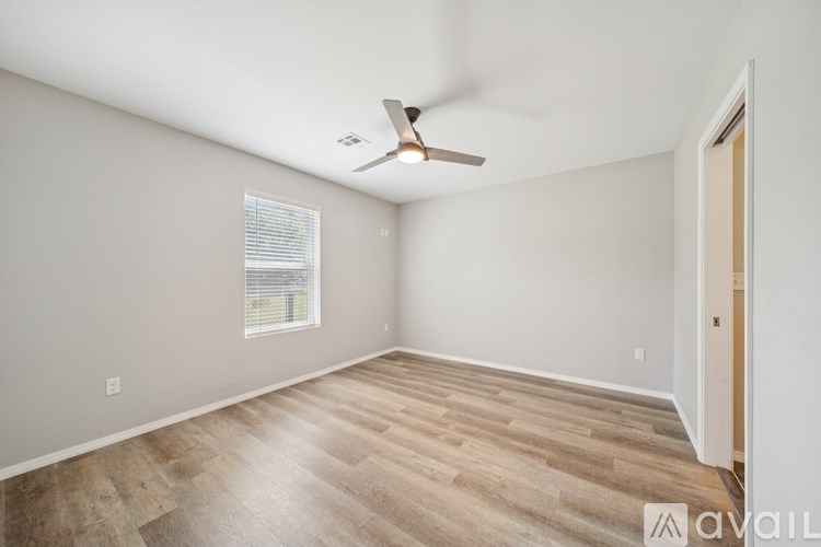 A room with a ceiling fan and wooden flooring.