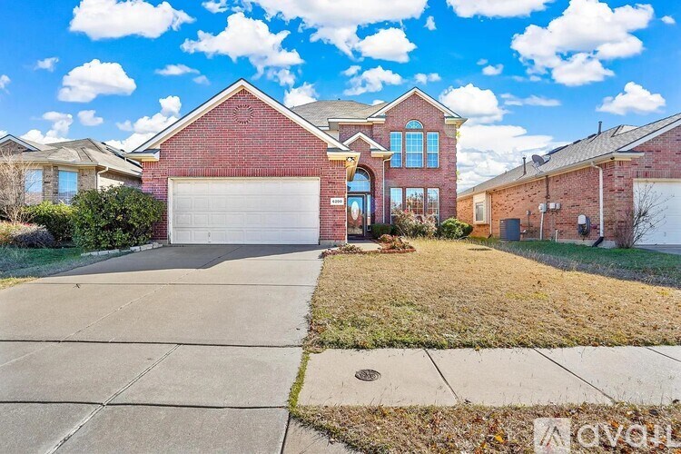A red brick house with a white garage door and a driveway.