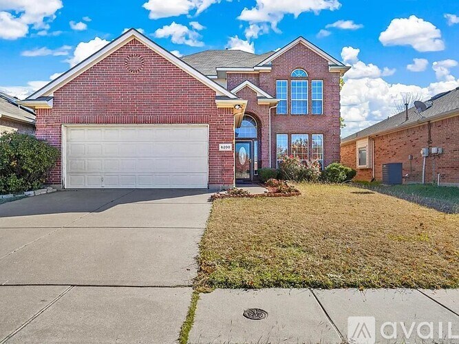 A red brick house with a white garage door and a driveway.