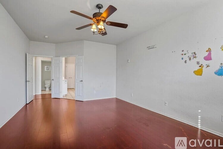 A room with a ceiling fan and wooden flooring.