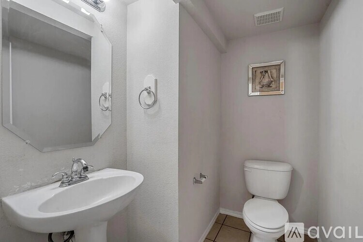 A bathroom with a toilet, sink, and mirror.