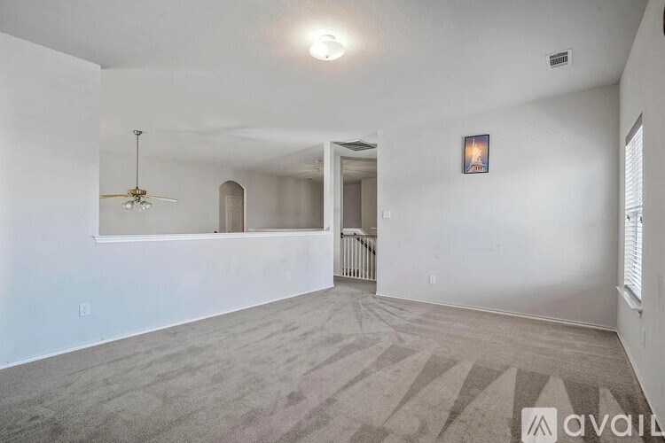 A spacious room with a carpeted floor and a ceiling fan.
