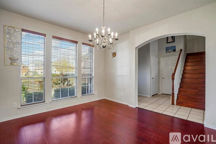 A room with a chandelier, a staircase, and a window with blinds.