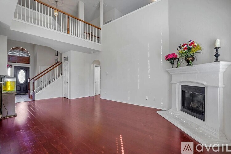 A large, empty room with a fireplace and a staircase.