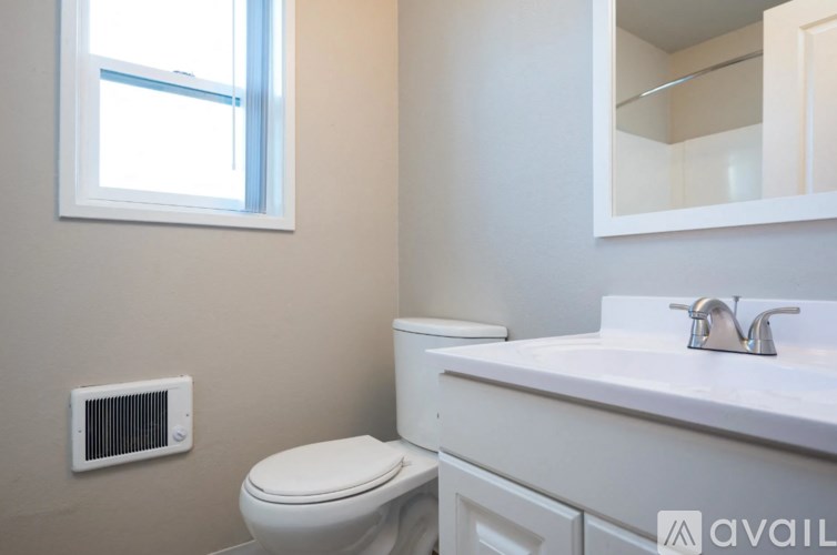 A bathroom with a toilet, sink, and window.