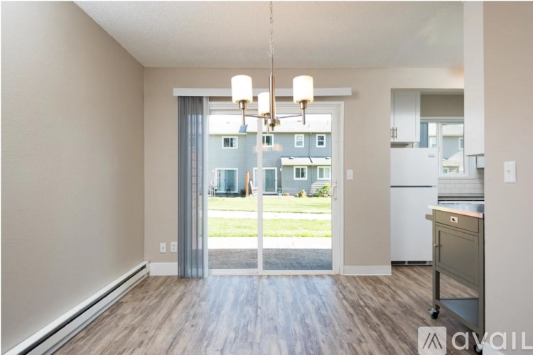 A kitchen area with a fridge, a dining table and a view of a building outside.