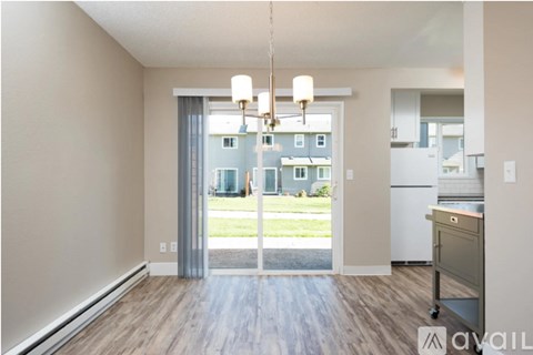 A kitchen area with a fridge, a dining table and a view of a building outside.