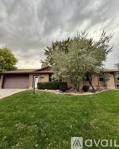 A house with a tree in front and a cloudy sky above.