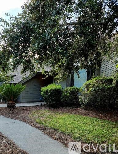 A house with a green lawn and a tree in front.