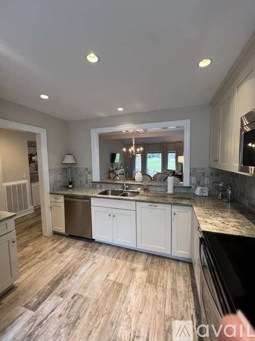 A kitchen with wooden flooring and white cabinets.