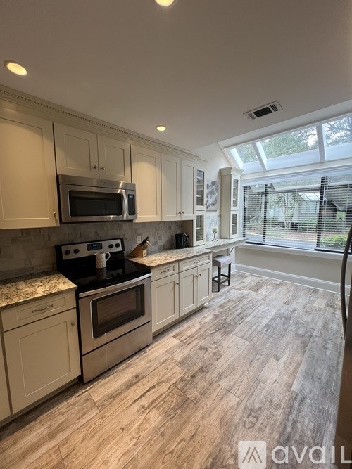 A kitchen with wooden floors and a stove top oven.