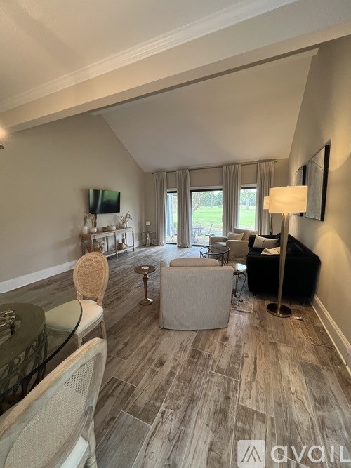 A living room with a glass table and chairs, a sofa, and a television.
