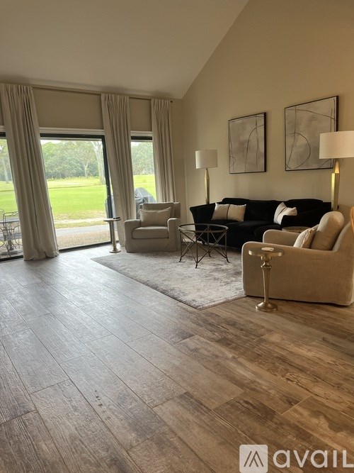 A living room with a couch, chairs, and a rug in front of a large window.
