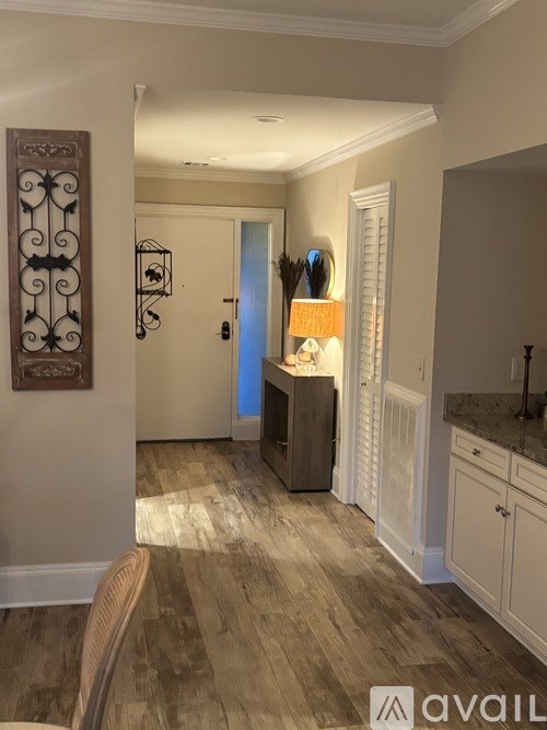 A well-lit hallway with a wooden floor and a white door.