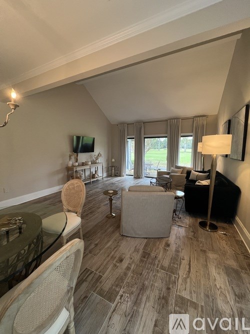 A living room with a glass table and chairs, a sofa, and a television.