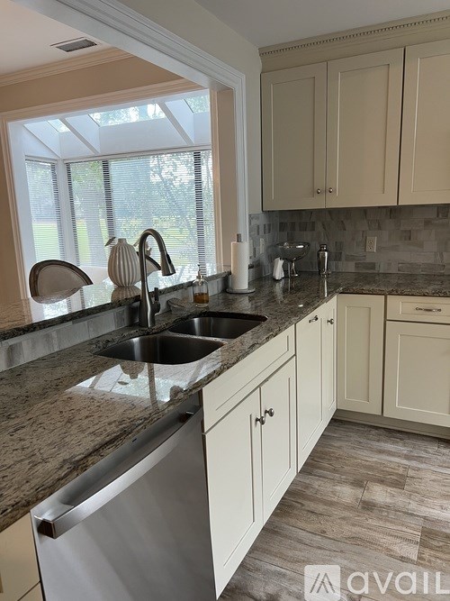 A kitchen with a granite countertop and a stainless steel dishwasher.