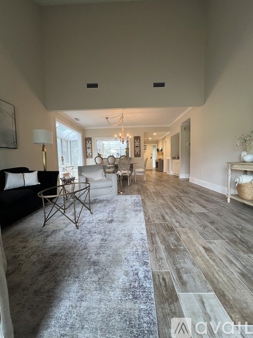 A living room with a black couch and a grey rug.