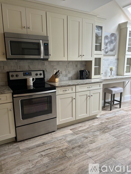A kitchen with a stove, oven, microwave, and cabinets.