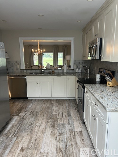 A kitchen with white cabinets and a wooden floor.