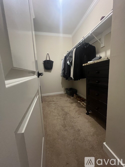 A hallway with a coat closet and a purse hanging on the wall.