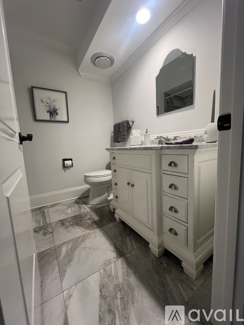 A bathroom with a toilet, sink, and mirror.