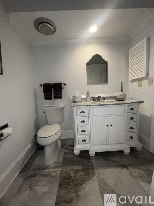 A bathroom with a toilet, sink, and mirror.