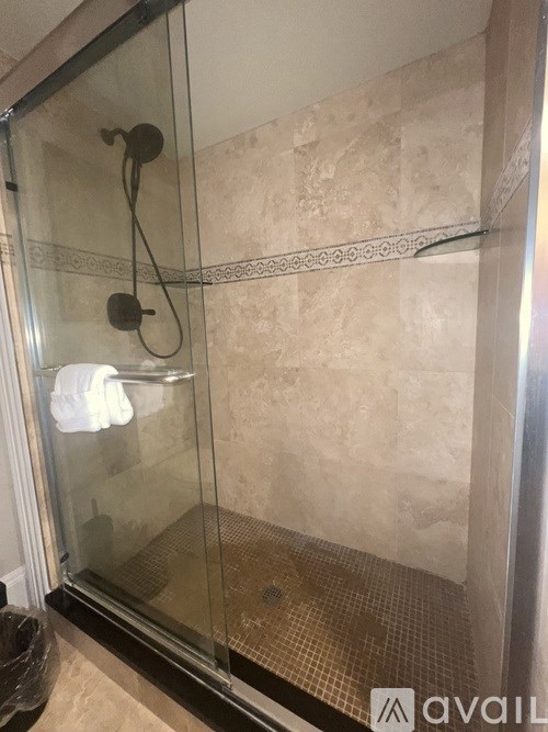A shower with a glass door and a tiled floor.