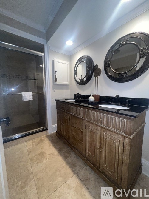 A bathroom with a wooden vanity and a round mirror above it.
