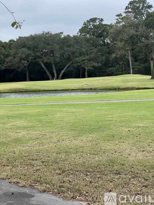 A golf course with a pond and trees in the background.