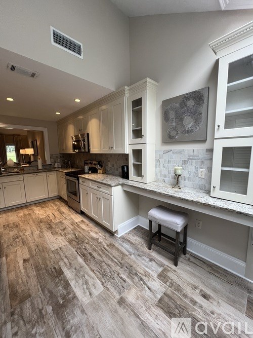 A kitchen with wooden floors and white cabinets.
