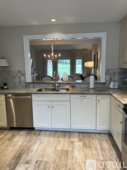 A kitchen with white cabinets and a wooden floor.