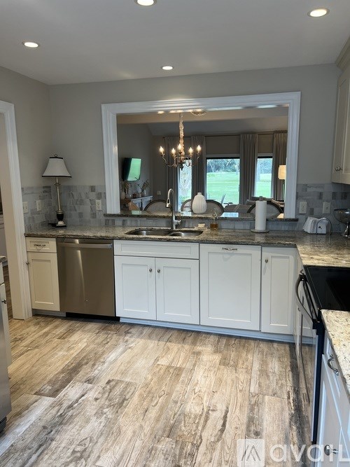 A kitchen with white cabinets and a wooden floor.