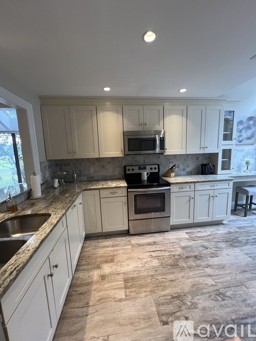 A kitchen with a sink, stove, and cabinets.