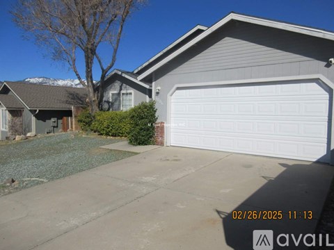 A house with a white garage door and a tree in front.